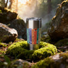 Stainless steel tumbler with Agatha Christie Book spines on a mossy rock in a forest setting
