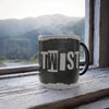 Mug with 'PLOT TWIST' on a wooden surface with a mountain view