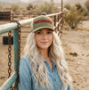 Woman wearing a cap with 'Protagonist' text in a desert setting