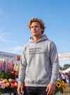 A man wearing a light gray hoodie with the text 'READ BOOKS. WALK DOGS. FIGHT FASCISTS.