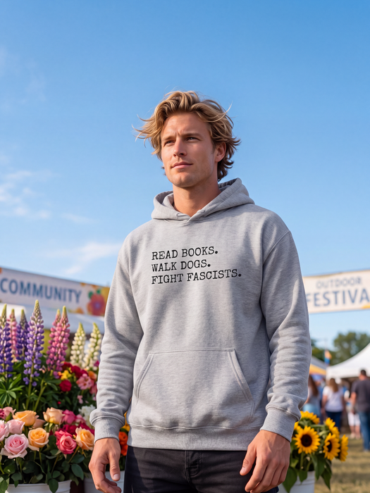 A man wearing a light gray hoodie with the text 'READ BOOKS. WALK DOGS. FIGHT FASCISTS.