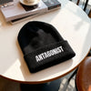 Black beanie with 'ANTAGONIST' text on a white table